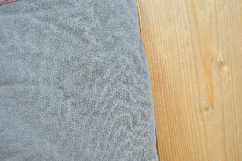 May include: Close-up of a section of a light blue fabric with a textured surface. The fabric is slightly wrinkled. The right side of the image shows a section of a light brown wooden surface.