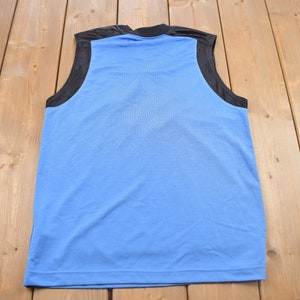 May include: A sleeveless blue athletic shirt with black trim around the armholes and neck.