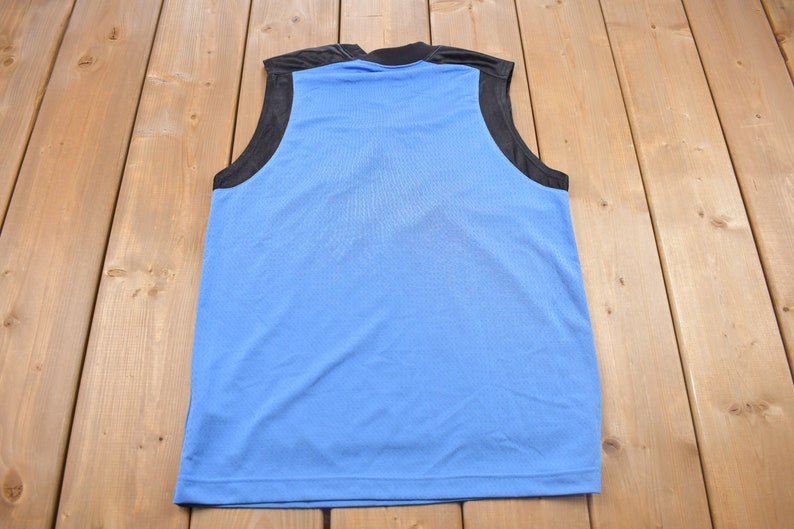 May include: A sleeveless blue athletic shirt with black trim around the armholes and neck.