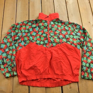May include: A red, green and blue patterned jacket with a zip closure. The jacket has a half-zip design and a drawstring at the bottom.