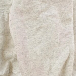 Op de afbeelding: Een lichtgrijs gem&ecirc;leerd sweatshirt met een zachte, fleeceachtige textuur over de gehele stof. Het kledingstuk vertoont een consistent gespikkeld patroon met donkerdere grijze vezels geweven in het lichtgrijze basismateriaal voor een klassieke uitstraling.