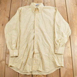 May include: A yellow and black checked long-sleeved button-down shirt.