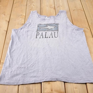 May include: A light gray sleeveless shirt with a graphic of a shark and the word "PALAU" printed on the front.