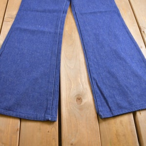 Op de afbeelding: Een paar blauwe denim bellbottom broeken met een brede pijpopening.