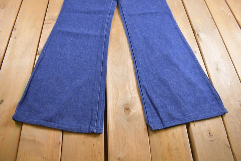 Op de afbeelding: Een paar blauwe denim bellbottom broeken met een brede pijpopening.
