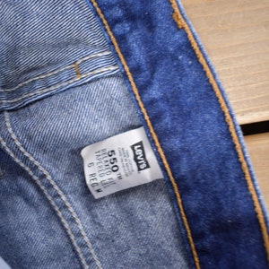 May include: A blue Levi's 550 Relaxed Fit Tapered Leg jean label with the size 6 Reg. W.