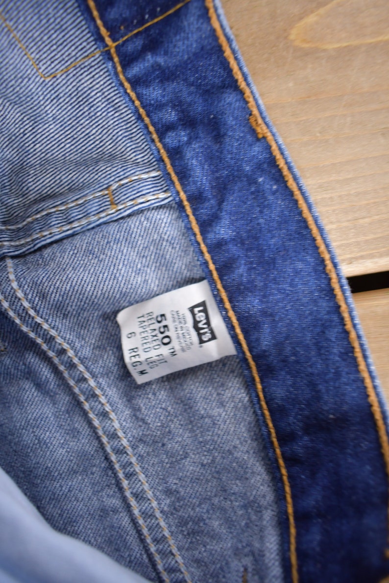 May include: A blue Levi's 550 Relaxed Fit Tapered Leg jean label with the size 6 Reg. W.