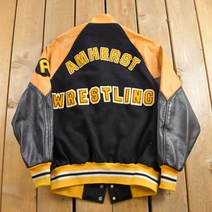 May include: Black and gold varsity jacket with "Amherst Wrestling" embroidered on the back. The sleeves are black leather and the body is wool.