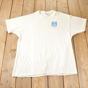 以下が含まれることがあります： 白いTシャツに、青い正方形のロゴがあり、白い文字で「The War on Drugs」と書かれています。