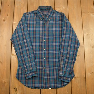 May include: A long-sleeved button-down shirt with a green, blue and red plaid pattern.