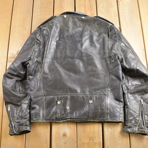 Puede incluir: Una chaqueta de cuero negra para motocicleta con cierre de cremallera y cuello con bot&oacute;n a presi&oacute;n. La chaqueta tiene un aspecto desgastado y est&aacute; usada.