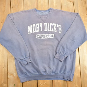 Puede incluir: Una sudadera azul claro con un estampado blanco que dice "Moby Dick's Cape Cod".