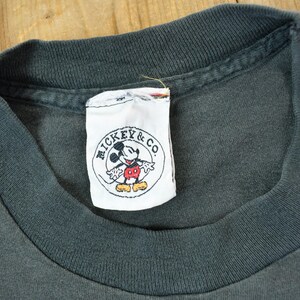 May include: A black t-shirt with a white tag that says "Mickey & Co." and features a cartoon image of Mickey Mouse.