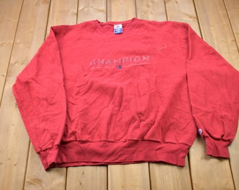 May include: Red Champion sweatshirt with a white embroidered logo that says "Champion" with a "C" logo underneath.