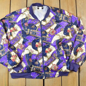 May include: A purple, blue, and gold patterned satin bomber jacket with a zipper closure.
