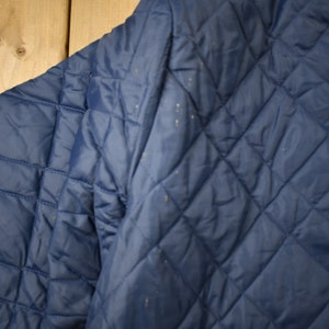 May include: A navy blue quilted jacket with a diamond pattern. The jacket is made of a soft, comfortable material and has a relaxed fit.