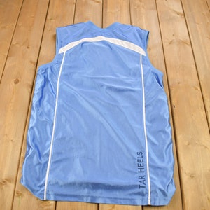 May include: A light blue sleeveless shirt with white trim and the text "TAR HEELS" on the back.