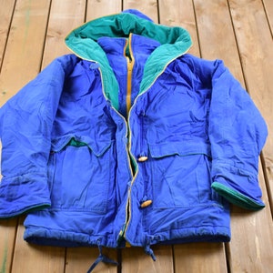 May include: A blue jacket with a green and yellow hood. The jacket has a zipper closure and two pockets.