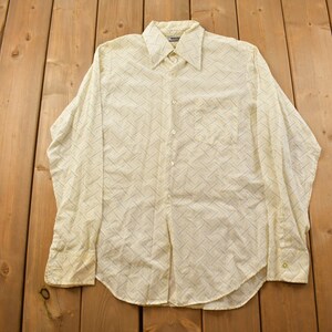 May include: A white long-sleeved button-down shirt with a geometric pattern in blue and yellow.