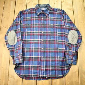 May include: A blue, red, and white plaid long-sleeve shirt with elbow patches.
