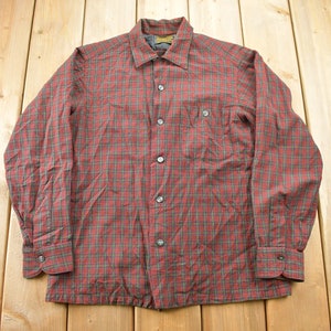 May include: Red and grey checked button-down shirt with long sleeves. The shirt features a classic collar, a chest pocket, and buttoned cuffs. The shirt is made of a soft material, possibly flannel.