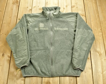 May include: A green fleece jacket with a zipper closure and two pockets on the chest. The jacket has a high collar and a drawstring at the bottom.