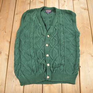 May include: A dark green cable knit vest with a v-neck and five gold buttons.
