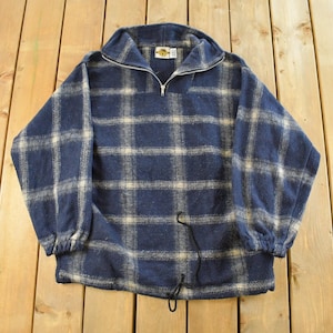 May include: A blue and white checked fleece pullover with a half-zip collar. The pullover features a drawstring at the hem and elasticated cuffs. The Hard Rock Cafe logo is visible on the collar.