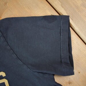 May include: A black t-shirt with the word "INS" in yellow lettering.