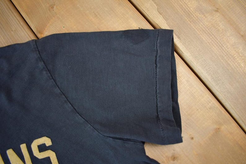 May include: A black t-shirt with the word "INS" in yellow lettering.