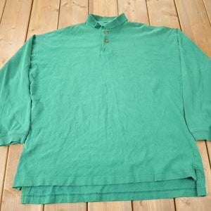 May include: A long-sleeved, green shirt with a button-up collar. The shirt has a relaxed fit and is made of a soft material. The shirt has a classic design, suitable for casual wear. The shirt has a length of approximately 76 cm.