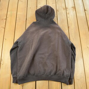 May include: A dark gray hooded sweatshirt with a drawstring hood, long sleeves, and a ribbed hem and cuffs. The sweatshirt is made of a soft, comfortable material and is suitable for casual wear.