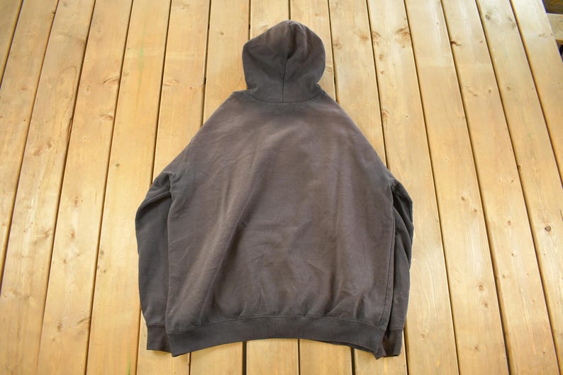 May include: A dark gray hooded sweatshirt with a drawstring hood, long sleeves, and a ribbed hem and cuffs. The sweatshirt is made of a soft, comfortable material and is suitable for casual wear.