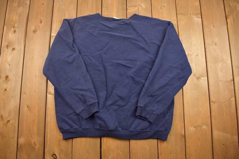 Puede incluir: Una sudadera de manga larga azul marino con cuello redondo.