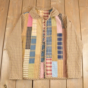 May include: A brown quilted jacket with a patchwork design featuring various shades of blue, red, and yellow plaid fabric.
