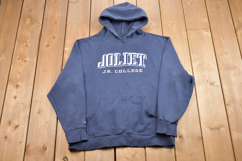 May include: A dark blue hooded sweatshirt with the text "Joliet Jr. College" in white lettering.