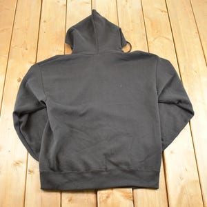 May include: A black hooded sweatshirt with a drawstring and a ribbed hem and cuffs. The back of the sweatshirt is visible, and it is made of a soft, comfortable material. The hoodie is a classic style.