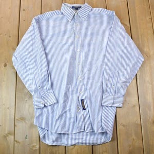 May include: A long-sleeved, button-down shirt with a white and blue striped pattern. The shirt has a classic collar and a single chest pocket.