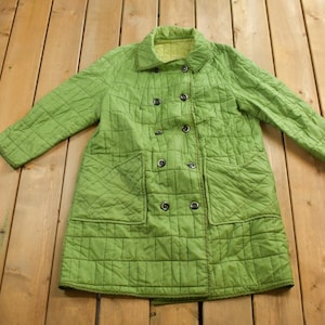 May include: A green quilted double-breasted coat with a stand-up collar.