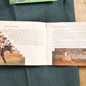 Op de afbeelding: Twee pagina's uit een boek over rodeo-evenementen. De linkerpagina toont een vrouw die op een bokkend paard rijdt in een rodeo-arena. De rechterpagina toont een man die een kalf lassoeert in een rodeo-arena. De tekst op de pagina's beschrijft de evenementen.