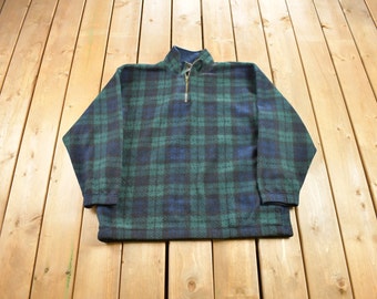 May include: A green and blue plaid fleece pullover with a quarter zip closure.