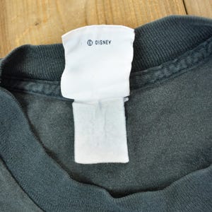 May include: A dark gray t-shirt with a white tag that says "&copy; DISNEY".