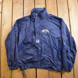 Puede incluir: Una chaqueta cortavientos azul marino con un logotipo blanco de "Penn State" en la parte delantera. La chaqueta tiene una cremallera y una capucha con cordón.