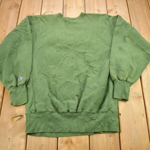 May include: A green Champion sweatshirt with a small logo on the left sleeve.