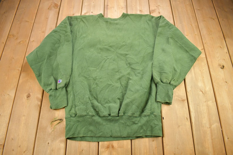 May include: A green Champion sweatshirt with a small logo on the left sleeve.