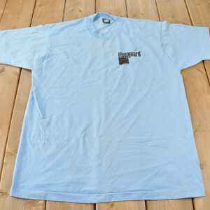 May include: A light blue t-shirt with a black logo that says "Fleetguard" on the front.