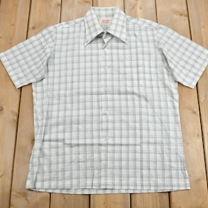 May include: A white and black checked short-sleeved button-down shirt with a collar.