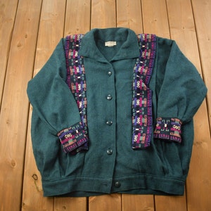May include: A teal green button-up cardigan with a colourful geometric pattern on the front and cuffs.