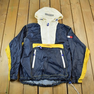 May include: A blue and yellow hooded jacket with a white zipper and a Tommy Hilfiger logo on the right sleeve.