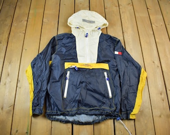 May include: A blue and yellow hooded jacket with a white zipper and a Tommy Hilfiger logo on the right sleeve.